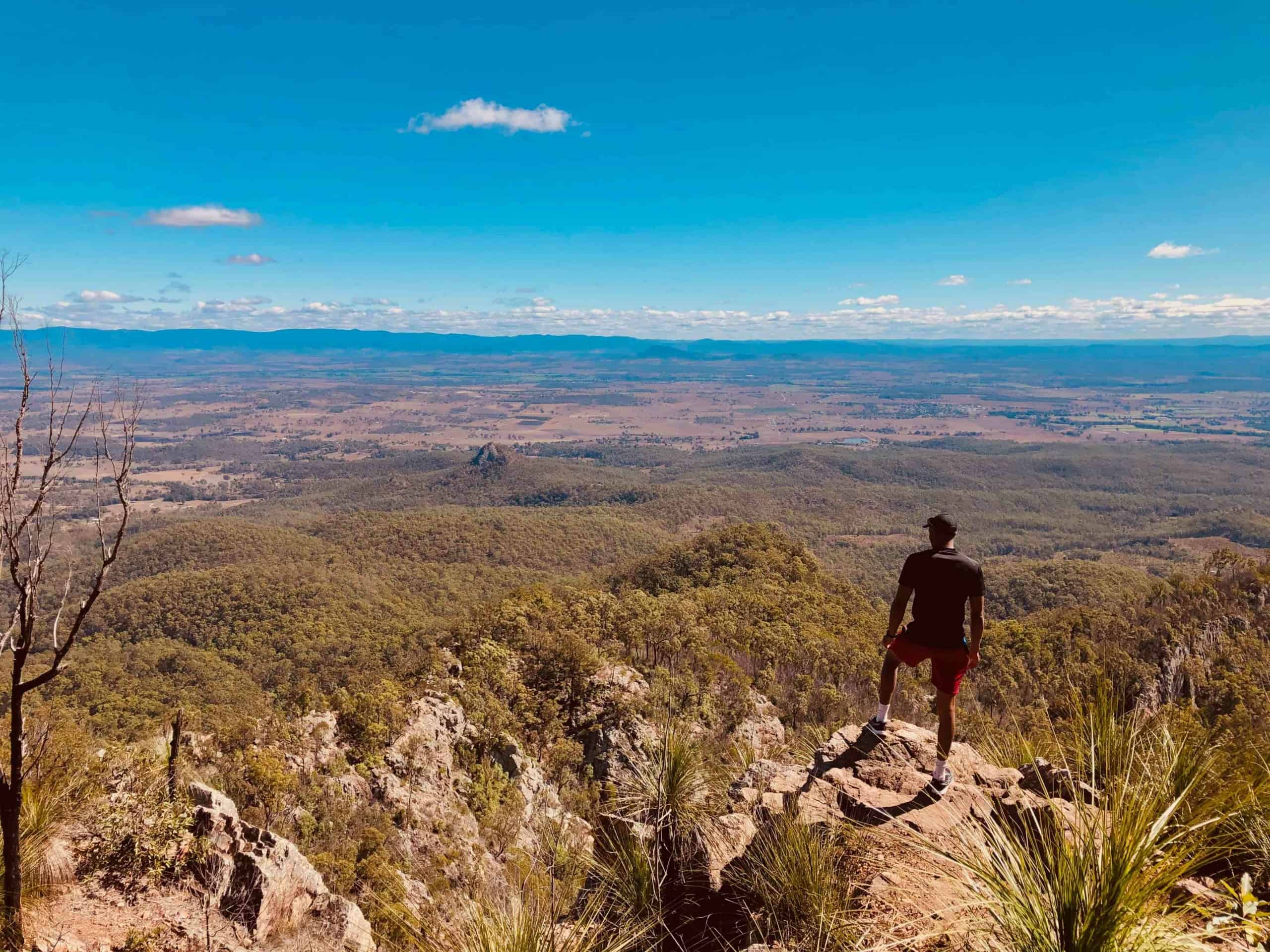 Man standing on cliff top overlooking Australian wilderness landscape