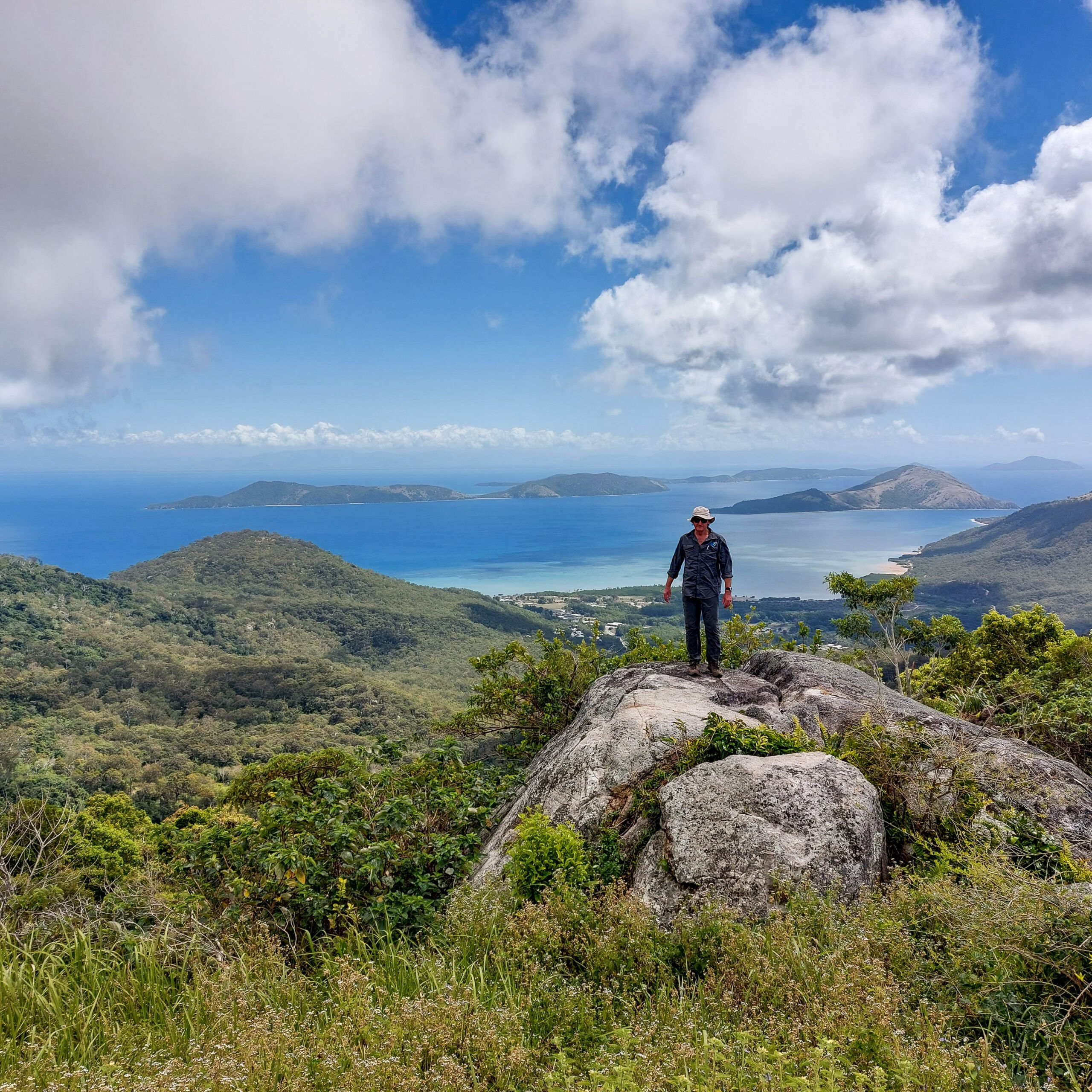 Chris Halstead pictured standing ontop of a rock. Behind him a stunning view of the beaches of Palm Island.